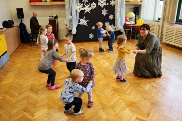 grupa dzieci z nauczycielką w trakcie zabawy z instrumentami