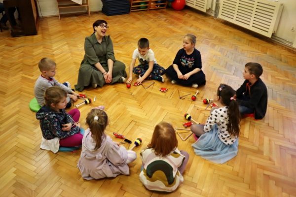 grupa dzieci z nauczycielką w trakcie zabawy z instrumentami