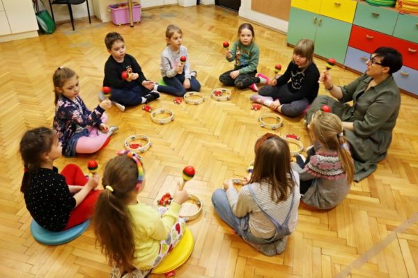 grupa dzieci z nauczycielką w trakcie zabawy z instrumentami