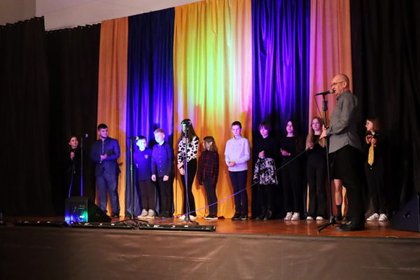 grupa wokalistów stojąca na scenie