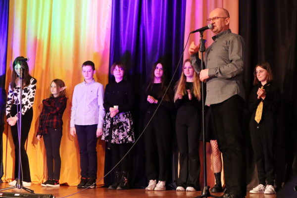 grupa wokalistów stojąca na scenie