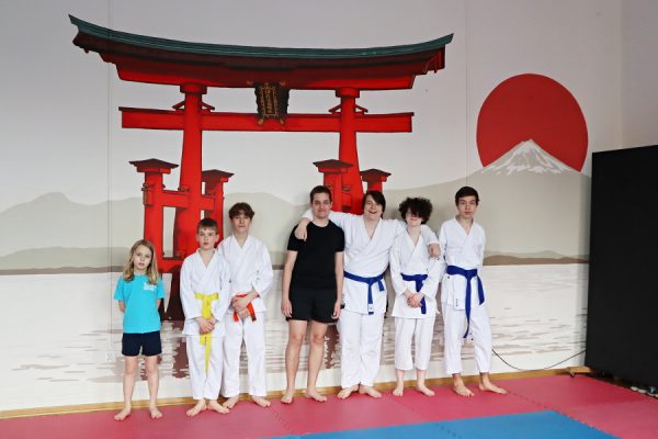 grupa uczestników pracowni karate w białych kimonach pozuje do zdjęcia