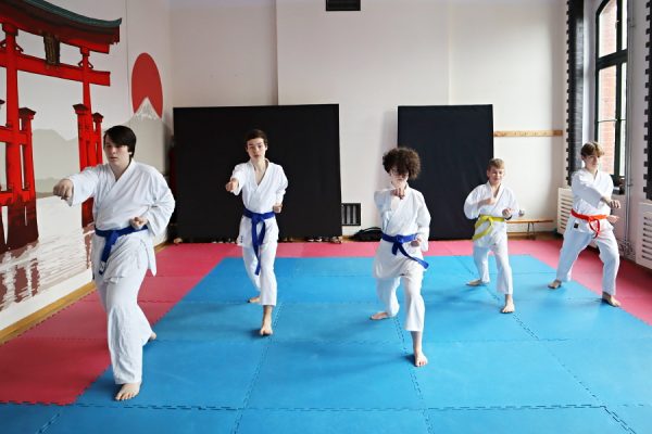 uczestnicy karate w białych kimonach podczas zajęć