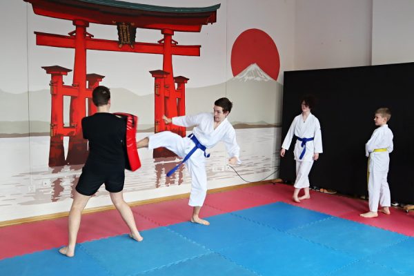 uczestnicy karate w białych kimonach podczas zajęć