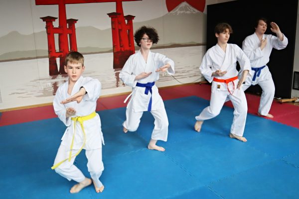 uczestnicy karate w białych kimonach podczas zajęć