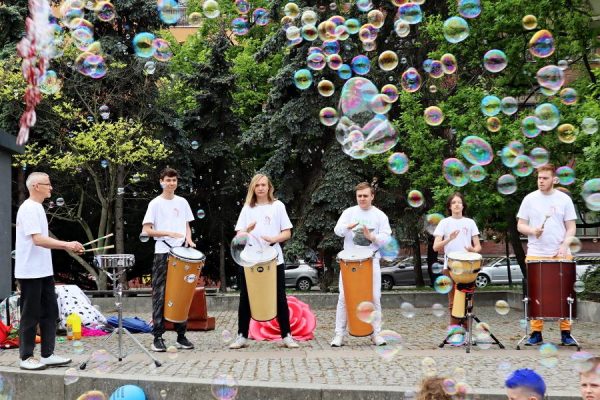 grupa młodzieży bębniąca na bębnach djembe nad nimi bańki mydlane