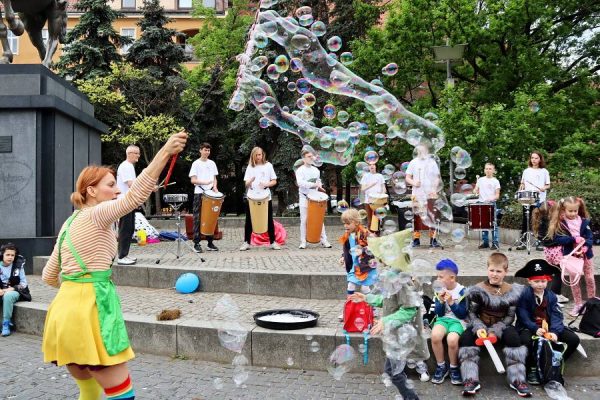 grupa młodzieży bębniąca na bębnach djembe nad nimi bańki mydlane