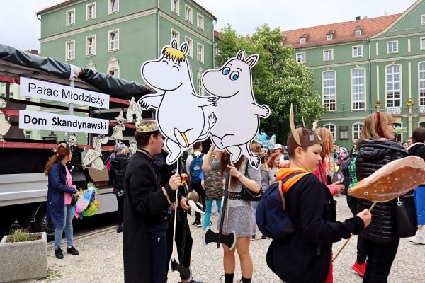 grupa młodzieży z postaciami Muminków na patyku