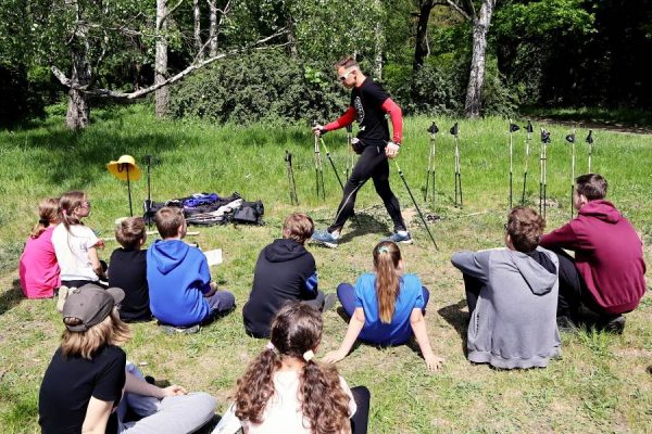 grupa uczniów z prowadzącym warsztaty który prezentuje kije nordic walking