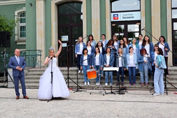 chór Uniwersytetu Szczecinskiego i witająca uczestników parady kobieta w balowej sukni