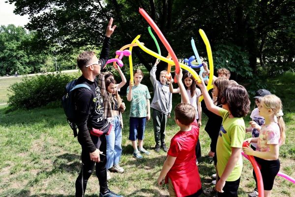 grupa uczniów z prowadzącym warsztaty dzieci trzymają kolorowe balony
