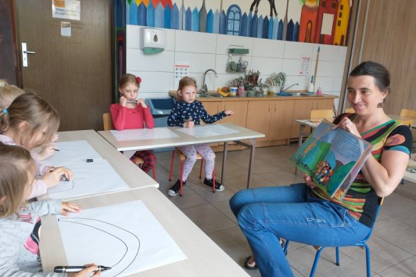 uczestnicy pracowni nauczyciel czyta książkę dzieciom