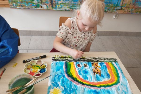 dziewczynka pochylona nad rysunkiem tęczy