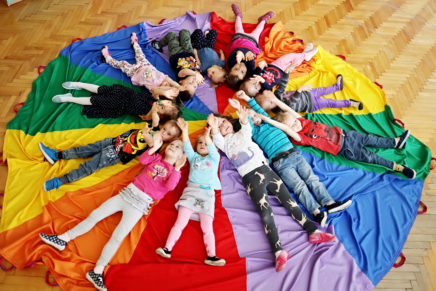 grupa dzieci leżaca na kolorowej chuście Klanzy