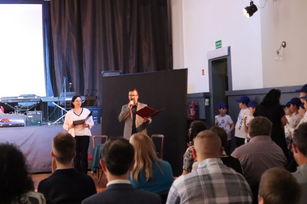 mężczyzna i kobieta stoja przed sceną z mikorofonami