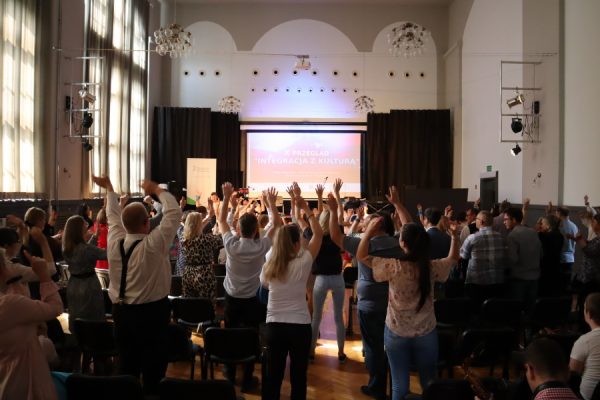 publiczność stoi na występie z rękami w górze