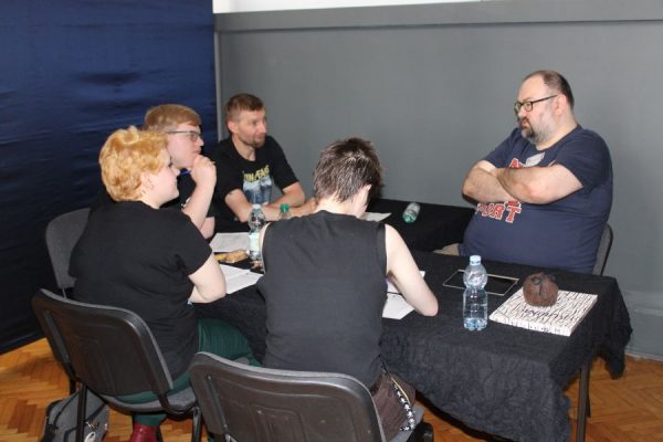 grupa młodzieży siedząca przy stole i grające w gry RPG