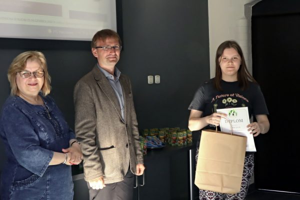 stojaca kobieta i mężczyzna obok nich dziewczyna z torbą papierową i dplomem