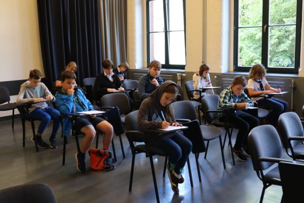 grupa dzieci siedząca i piszącch test