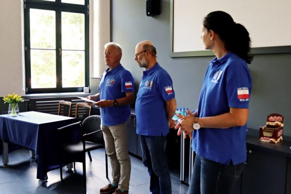 trzy osoby w niebieskich koszulkach z logo