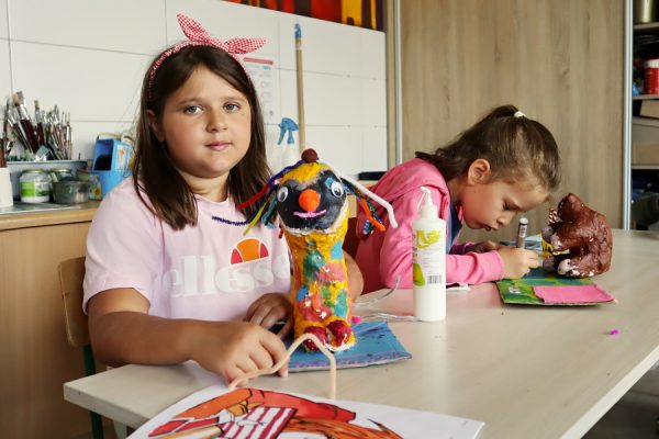 dziewczynka pozuje do zdjęcia w pracowni plastycznej