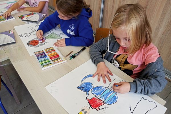 dwie dziewczynki rysują kredkami