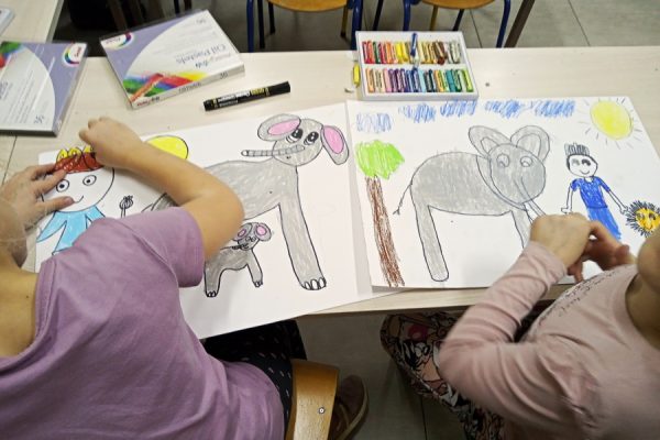 dwie dziewczynki rysują kredkami