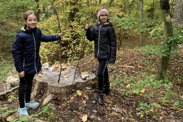 dwie dziewczynki stojące przy pniu drzewa
