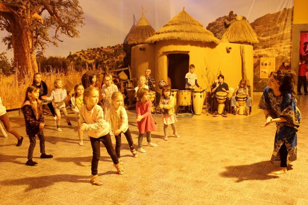 grupa dzieci tańczy w przestrzeni wioski afrykańskiej
