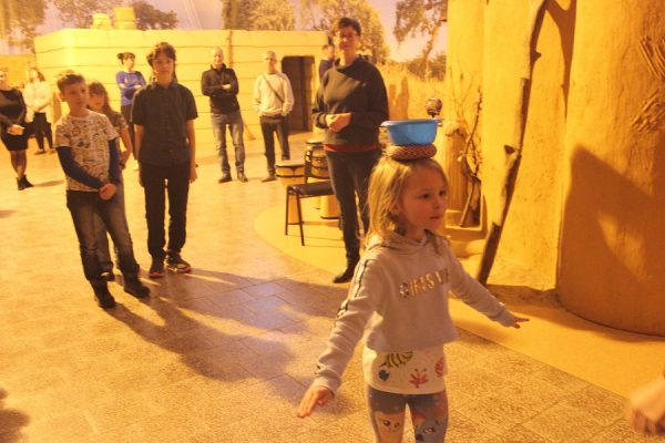 dziewczynka niesie na głowie miskę