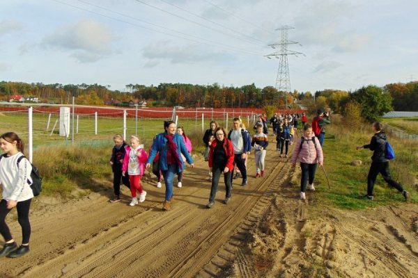 piaszczysta droga, grupa dzieci, w oddali drzewa i zabudowania