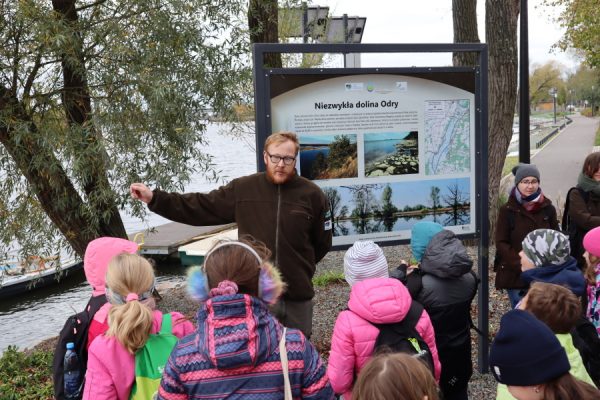 mężczyzna przy tablicy edukacyjnej opowiada coś dzieciom