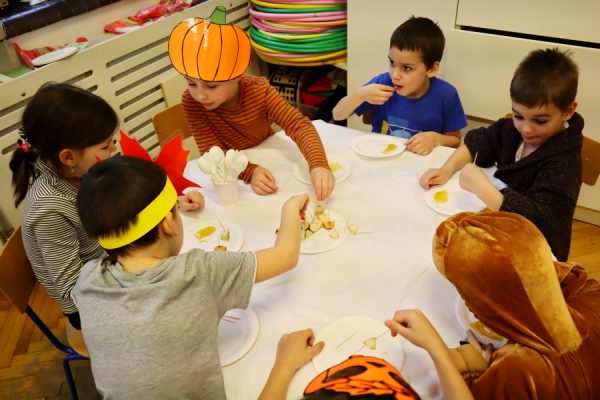 dzieci siedzą przy stole, jedzą owoce