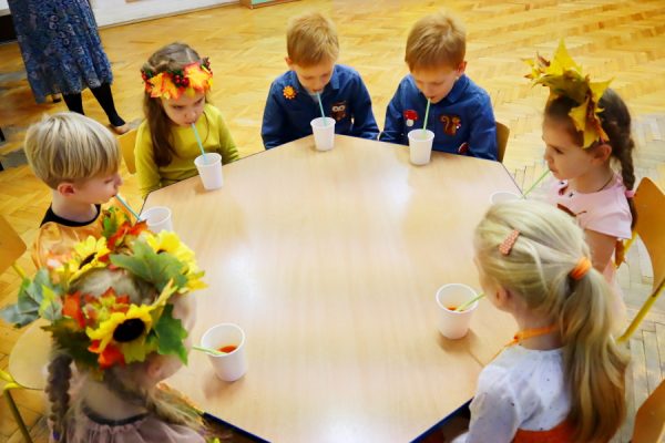 dzieci przy stoliku piją przez słomkę coś z kubeczków