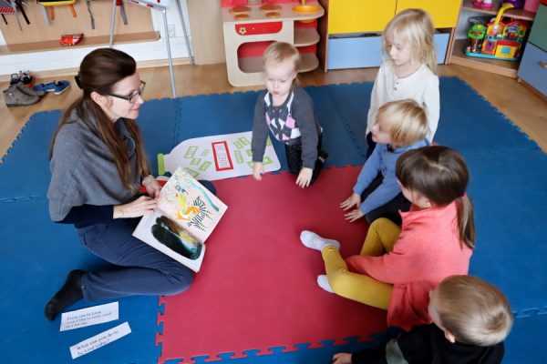 nauczycielka z dziećmi czyta im książkę