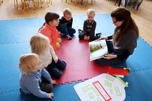 nauczycielka z dziećmi czyta im książkę