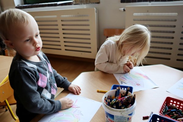 grupa dzieci siedzi przy stoliku i rysuje