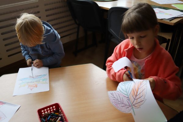 grupa dzieci siedzi przy stoliku i wycina