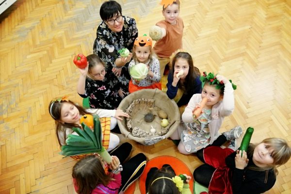 dzieci pochylone na koszem z warzywami