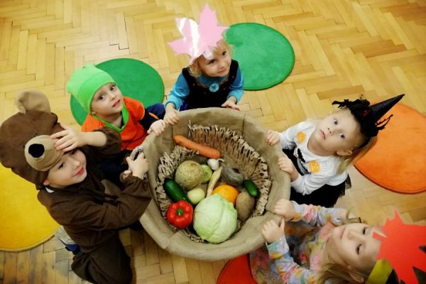 dzieci pochylone na koszem z warzywami