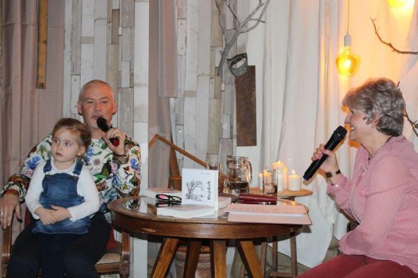 dwie osoby rozmawiają, u mężczyzny siedzi na kolanach dziecko