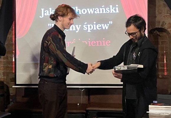 mężczyzna wręcza nagrodę młodemu chłopakowi