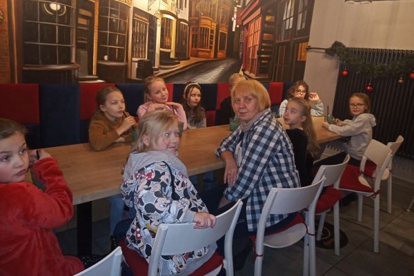 grupa dzieci z nauczycielką siedzi przy stole