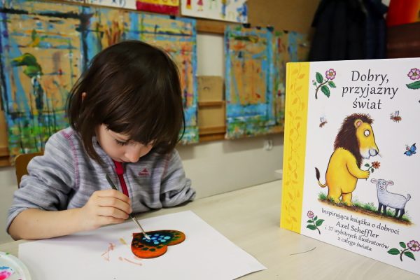 dziewczynka maluje obok książka