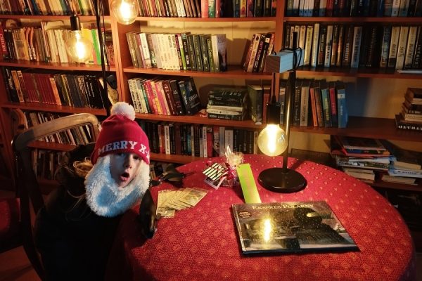 chłopiec w czapce mikołaja siedzi przy stole w bibliotece