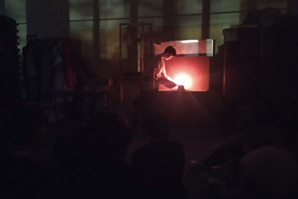 ciemne zdjęcie na środku chłopiec który przykłada woskowy kształt do świecy