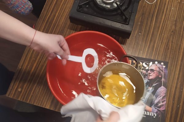 ręce trzymające garnek z woskiem