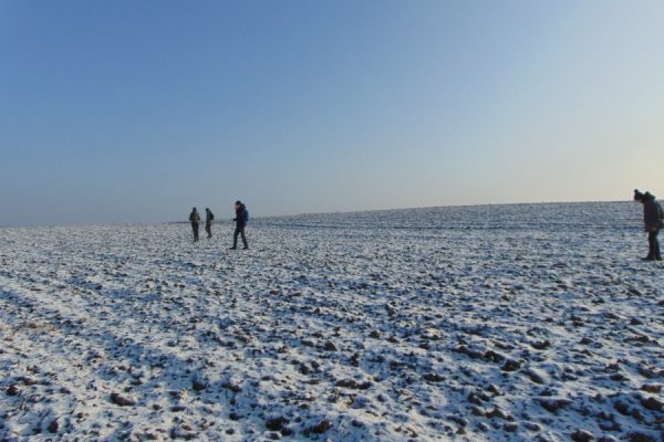 ośnieżone pole, w oddali młodzież