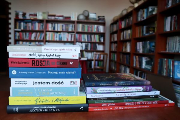 książki leżące ba biurku w tle regały biblioteczne