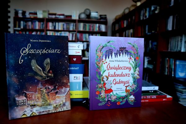 książki leżące ba biurku w tle regały biblioteczne